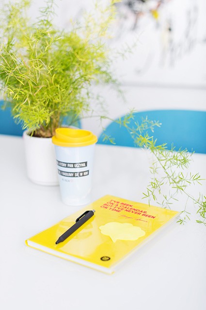Żółty notes Zip Cover z czarnym długopisem obok rośliny